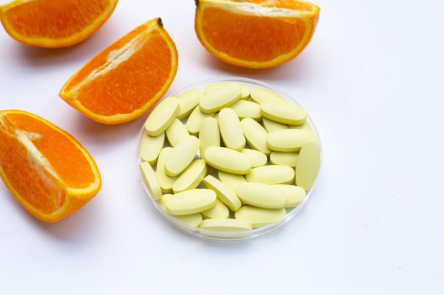 白い背景の上のオレンジ色の果物とビタミンCの丸薬
