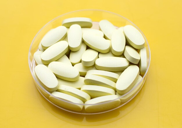 Vitamin C pills on yellow background