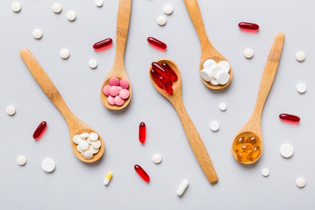 Vitamin capsules in a spoon on a colored background Pills served as a healthy meal Red soft gel vitamin supplement capsules on spoon