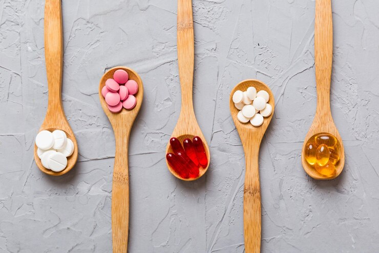 Photo vitamin capsules in a spoon on a colored background pills served as a healthy meal red soft gel vitamin supplement capsules on spoon
