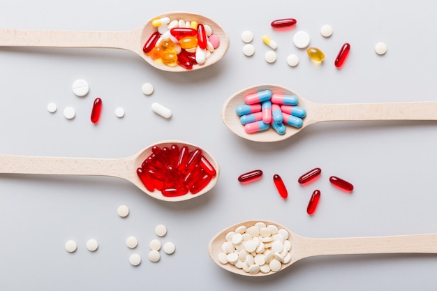 Vitamin capsules in a spoon on a colored background Pills served as a healthy meal Red soft gel vitamin supplement capsules on spoon