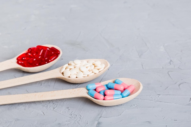 Vitamin capsules in a spoon on a colored background Pills served as a healthy meal Red soft gel vitamin supplement capsules on spoon