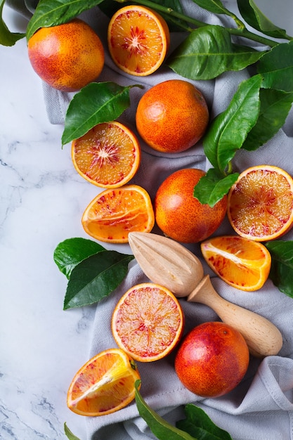 Vitamin, clean eating, healthy food vegan concept. Whole and sliced sweet sicilian blood oranges on a white marble table. Top view flat lay background