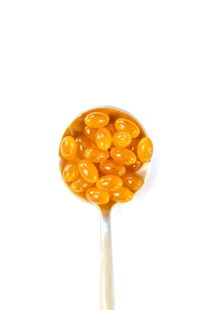 Vitamin D 3 supplement on a spoon isolate on a white background Selective focus Pills