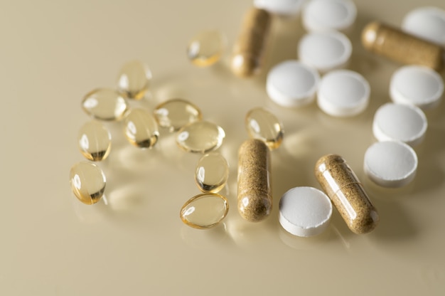 Vitamin D capsules zinc tablets scattered on a light background