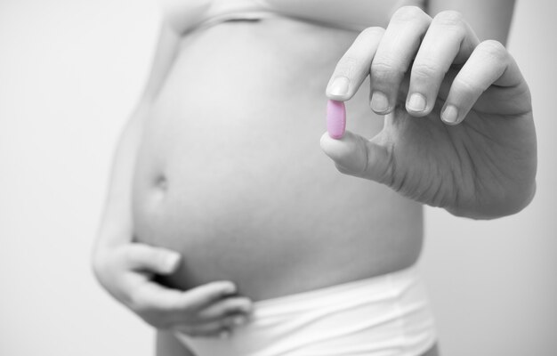 Vitamin pill in the hands of a pregnant woman