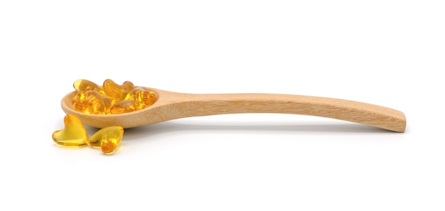 Vitamin pills and oil filled capsules in wooden spoon