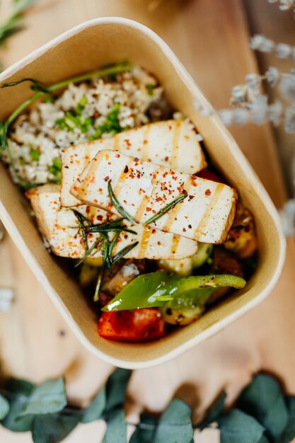 Фото Богатая витаминами веганская еда с тофу, кускусом, паприкой и грибами в эко-коробке с доставкой