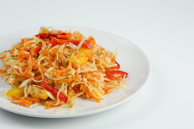 Vitamin salad with carrot cabbage and pepper closeup on white plate. fresh summer salad isolated on white