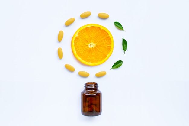 Vitamine C-fles en pillen met oranje fruit op wit