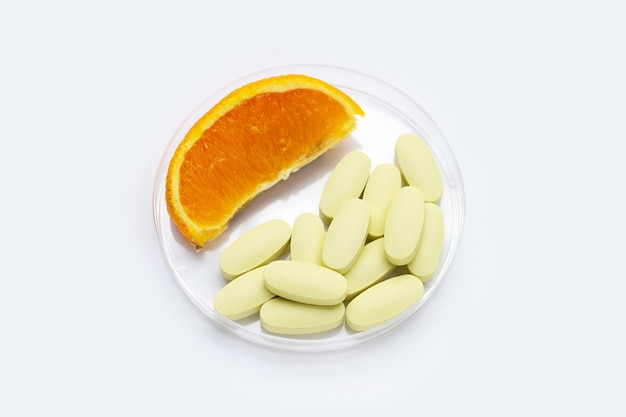 Vitamine c pillen met oranje fruit op witte achtergrond