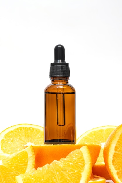 Vitamine C-serum in een amberblauwe fles met een pipet op een achtergrond van oranje citrusvruchten Citrus essentiële olie aromatherapie cosmetica Biologische SPA-cosmetica met kruideningrediënten