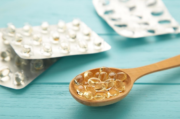Vitamine D gele pillen op houten lepel op blauwe achtergrond Medicijntabletten van vitamine d op tafel