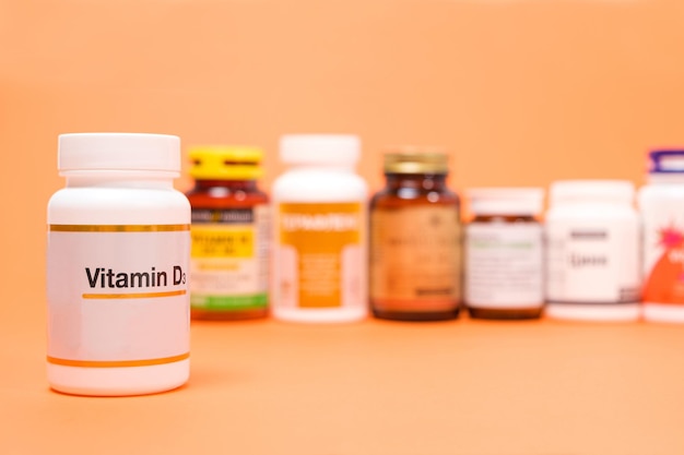 Vitamine D in een witte pot met andere voedingssupplementen op een oranje achtergrond