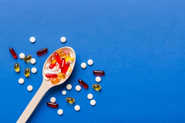 Vitaminecapsules in een lepel op een gekleurde achtergrond Pillen dienden als een gezonde maaltijd Rode zachte gel vitaminesupplementcapsules op lepel