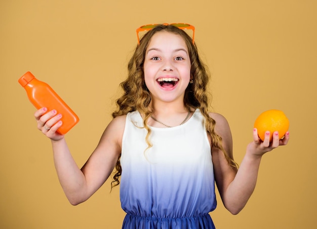 Vitaminevoeding Mode kinderzonnebril drink verfrissend vitaminesap Gezondheidszorg Zomer vitaminedieet Gelukkige jeugd Natuurlijke vitaminebron Kind meisje eet sinaasappelfruit en drinkt sinaasappelsap