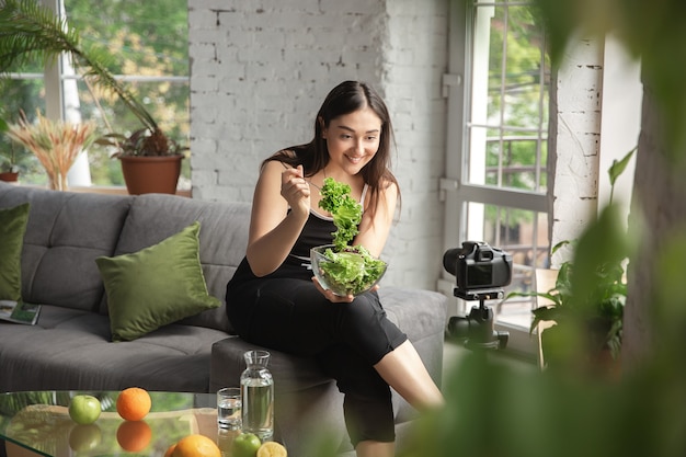 Photo vitamins. caucasian blogger, woman make vlog how to diet and lost weight, be body positive, healthy eating. using camera recording her green salad preparing. lifestyle influencer, wellness concept.