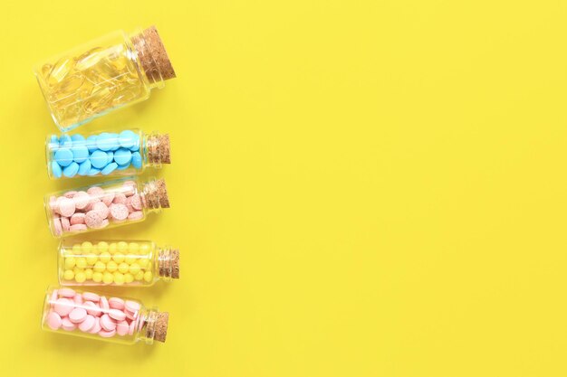 Vitamins in glass bottles on a yellow background top view Place for text copy space