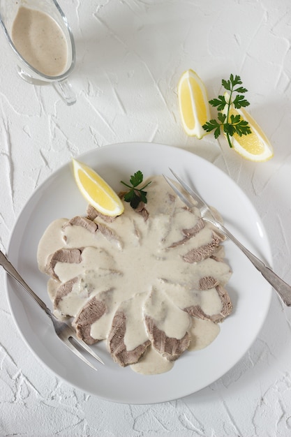 Vitello tonnato is a traditional italian dish on a white table.