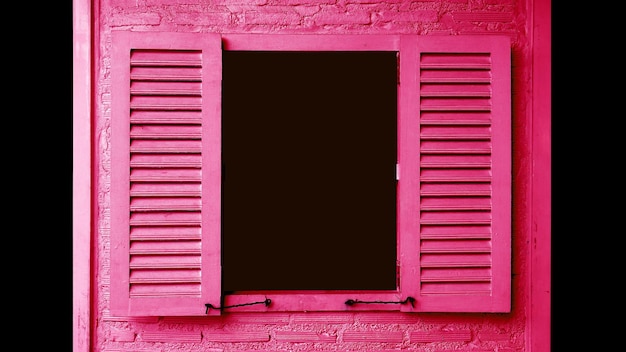 レンガの壁にシャッターが開く鮮やかなピンク色の木製窓