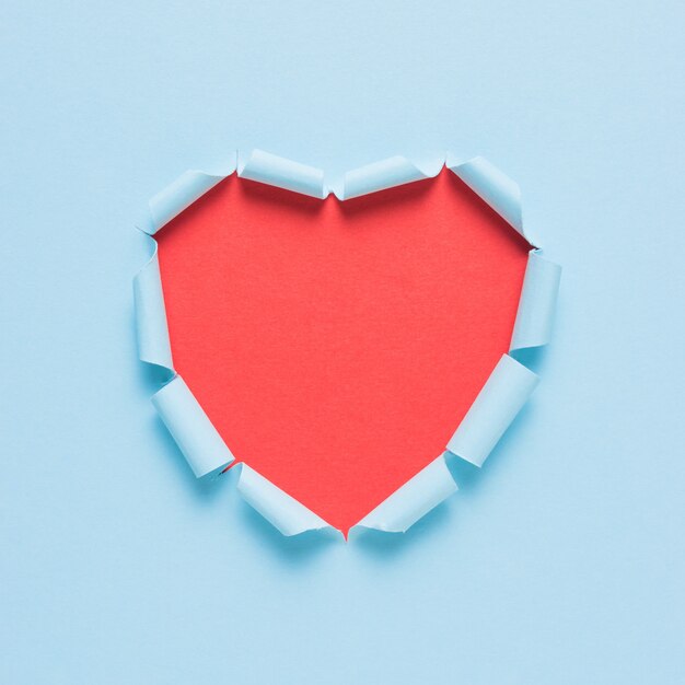 Vivid torn paper heart on bright background.