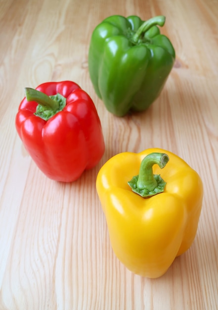 Vivid Tricolor Bell Peppers Isolated on Light Brown Wooden Table