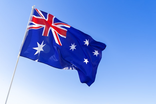 Vlag die van Australië tegen duidelijke blauwe hemel golven