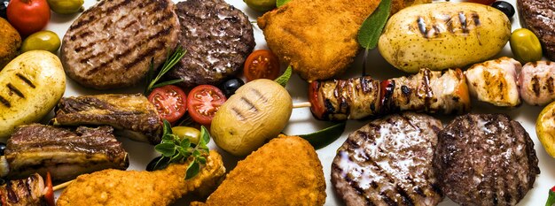 Vlag van BBQ-vleesfeest met verschillende soorten vlees: rundvleesburgers, varkensribbetjes, kalkoengehaktballetjes, kippendijen gepaneerd met aardappelen en tomaten, kruiden en aromatische kruiden.