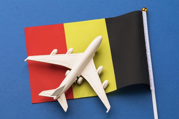 Vlag van België en een speelgoedvliegtuig op een blauw achtergrondconcept rond het thema reizen naar België