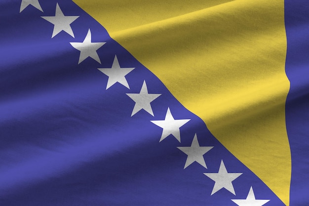 Vlag van Bosnië en Herzegovina met grote plooien die van dichtbij zwaaien onder het studiolicht binnenshuis De officiële symbolen en kleuren in banner