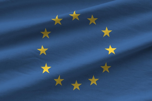 Vlag van de Europese Unie met grote plooien die van dichtbij zwaaien onder het studiolicht binnenshuis De officiële symbolen en kleuren in banner