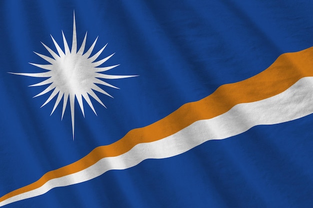 Vlag van de Marshalleilanden met grote plooien die van dichtbij zwaaien onder het studiolicht binnenshuis De officiële symbolen en kleuren in banner