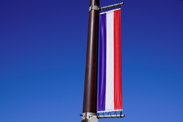 Vlag van Frankrijk hangt aan een lange mast voor een blauwe lucht