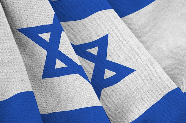 Vlag van Israël met grote plooien die van dichtbij zwaaien onder het studiolicht binnenshuis De officiële symbolen en kleuren in banner