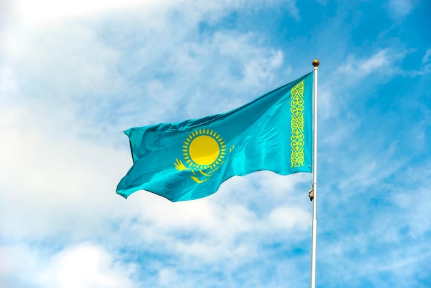 Vlag van kazachstan zwaaien tegen blauwe hemel