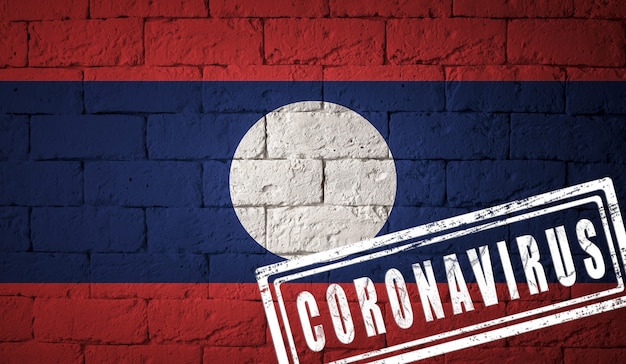 Vlag van laos met originele verhoudingen. gestempeld met het coronavirus. bakstenen muur textuur. corona-virusconcept. op de rand van een covid-19- of 2019-ncov-pandemie.