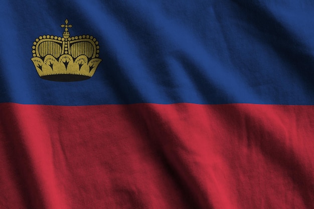 Vlag van Liechtenstein met grote plooien die van dichtbij zwaaien onder het studiolicht binnenshuis De officiële symbolen en kleuren in banner