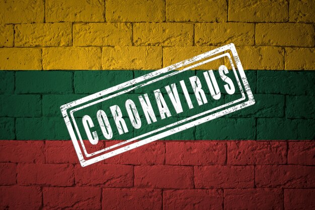 Vlag van Litouwen met originele verhoudingen. gestempeld met het Coronavirus. bakstenen muur textuur. Corona-virusconcept. Op de rand van een COVID-19- of 2019-nCoV-pandemie.