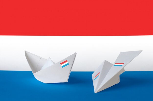 Vlag van luxemburg afgebeeld op papieren origami vliegtuig en boot. handgemaakt kunstconcept