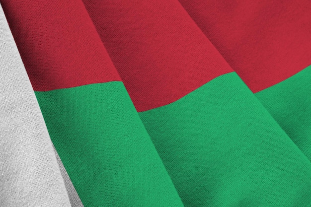 Vlag van Madagaskar met grote vouwen die dicht omhoog zwaaien onder het studiolicht binnenshuis De officiële symbolen en kleuren in banner