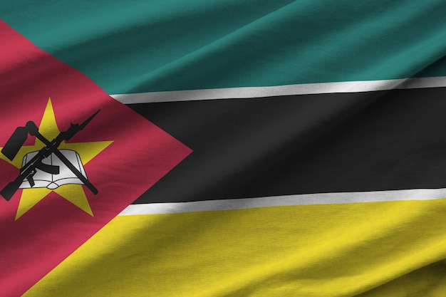 Vlag van Mozambique met grote plooien die dicht omhoog zwaaien onder het studiolicht binnenshuis De officiële symbolen en kleuren in banner