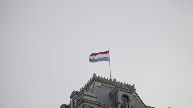 Vlag van nederland op de bovenkant van het gebouw voor de bewolkte hemel, telefoto