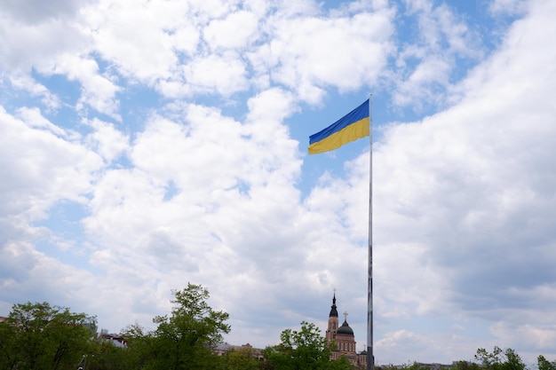 Vlag van Oekraïne op een hoge vlaggenmast geïsoleerd op een blauwe hemelachtergrond