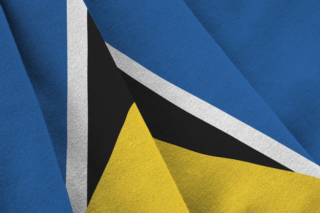 Vlag van Saint Lucia met grote plooien die van dichtbij zwaaien onder het studiolicht binnenshuis De officiële symbolen en kleuren in banner