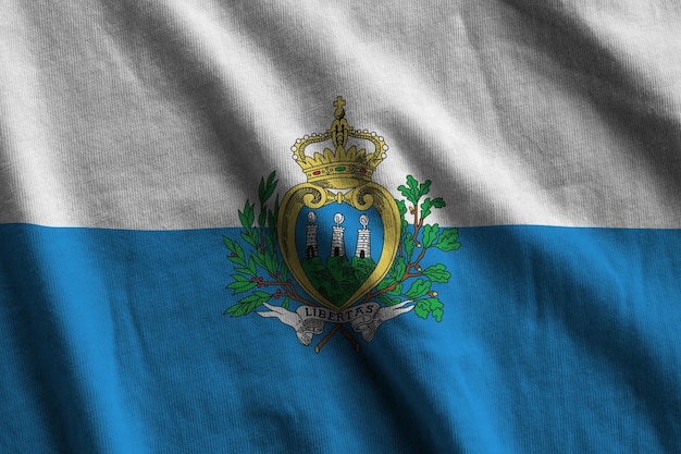 Vlag van San Marino met grote vouwen die van dichtbij zwaaien onder het studiolicht binnenshuis de officiële symbolen a