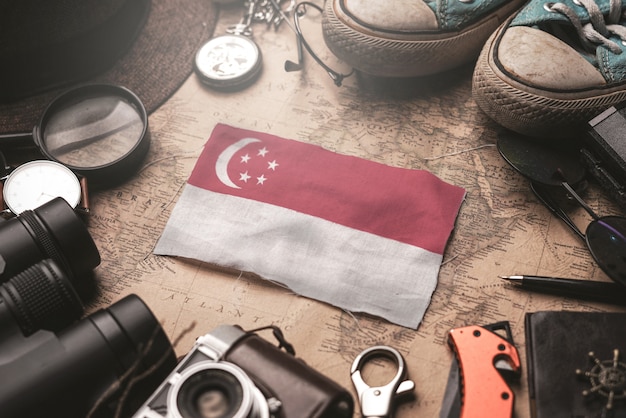 Vlag van Singapore tussen de accessoires van de reiziger op oude vintage kaart. Toeristische bestemming Concept.