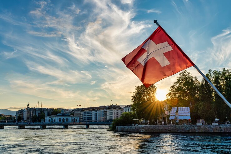 Vlag van Zwitserland op de voorgrond bij zonsondergang in de stad Genève, Zwitserland. meer van Leman.