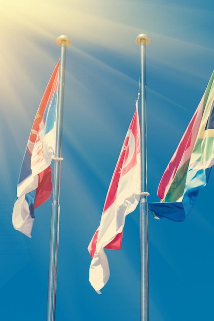 Vlaggen van verschillende landen op de achtergrond van de blauwe lucht in het zonlicht