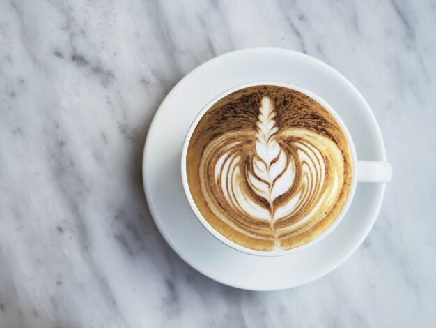 Foto vlak leg fotografie van koffie met mooie latte kunst op witte marmeren achtergrond.