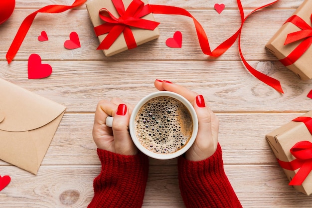 Vlak van hartvormige kop zwarte koffie in de handen van vrouwen op gekleurde achtergrond met kopieerruimte top view Valentijnsdag en vakantie concept